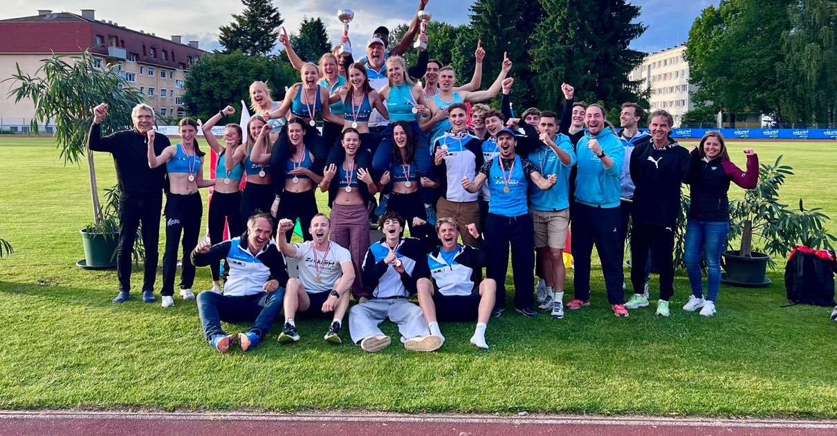 Die Mannschaft der TGW Zehnkampf-Union jubelt mit Medaillen und Pokalen auf dem Sportplatz